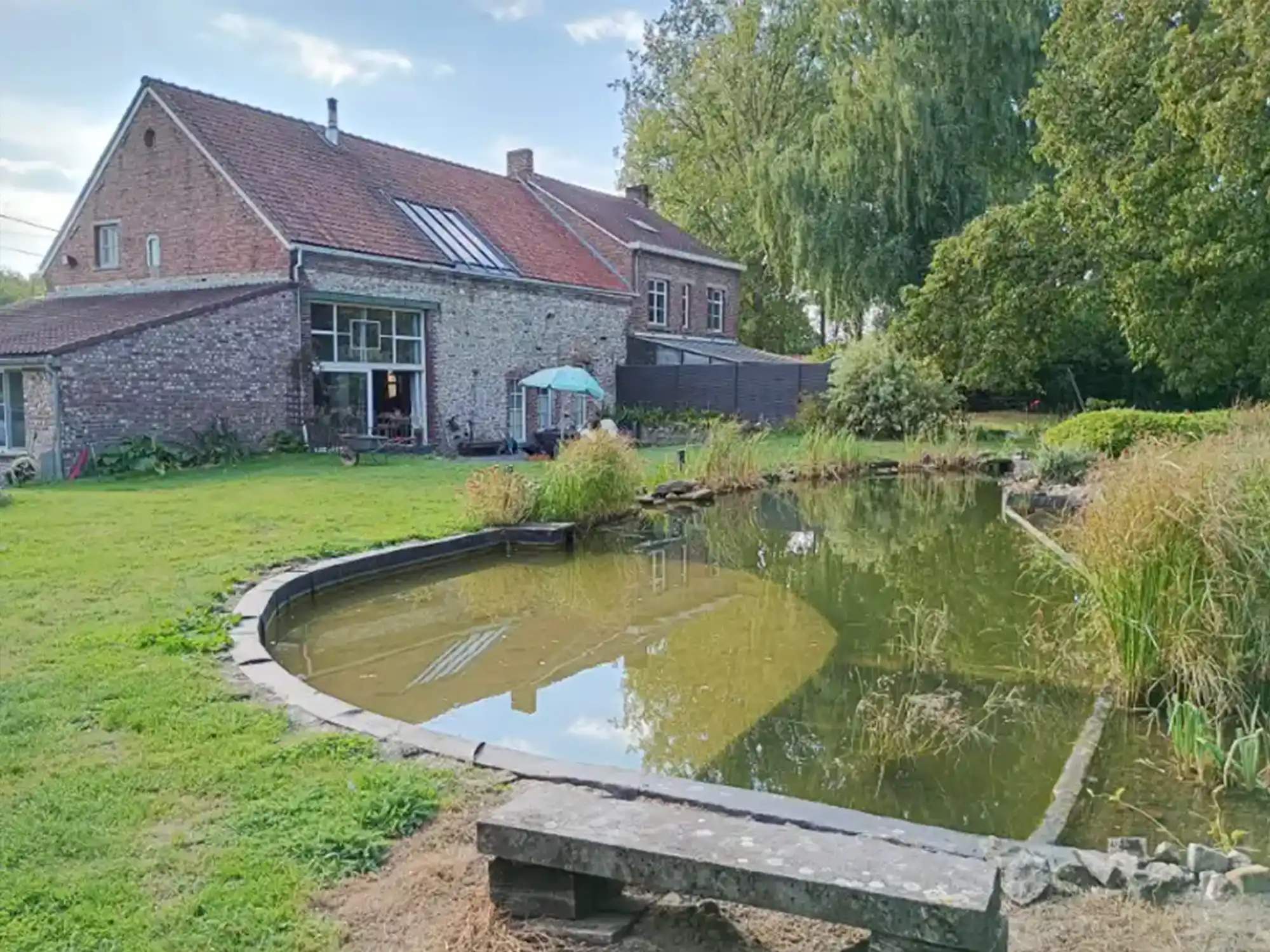 Jardin aménagé autour d'un étang près d'une ferme en briques